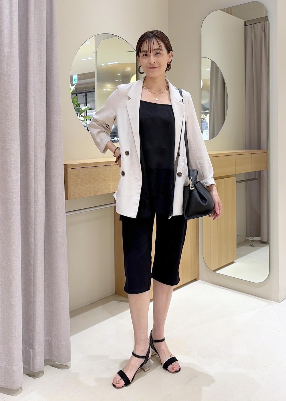 ホワイト系のテーラードジャケット、ブラック系のその他パンツ、ブラック系のショルダーバッグを着用したレディースの夏コーディネートの2枚目の写真
