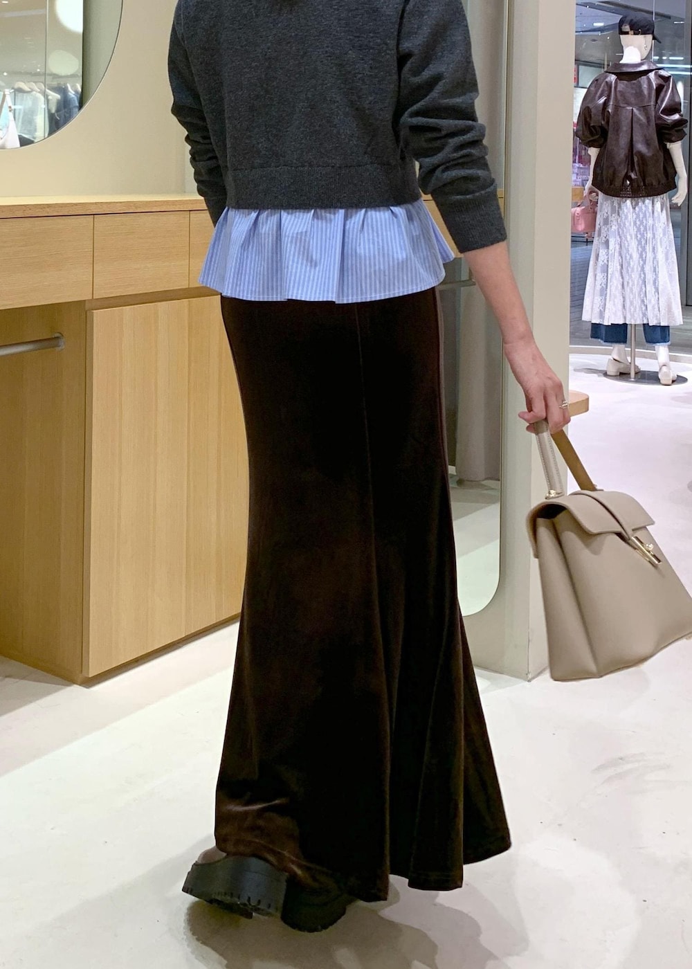 ベージュ系のハンドバッグ、ブラウン系のブーツ、ブラウン系のスカートを着用したレディースの秋コーディネートの8枚目の写真