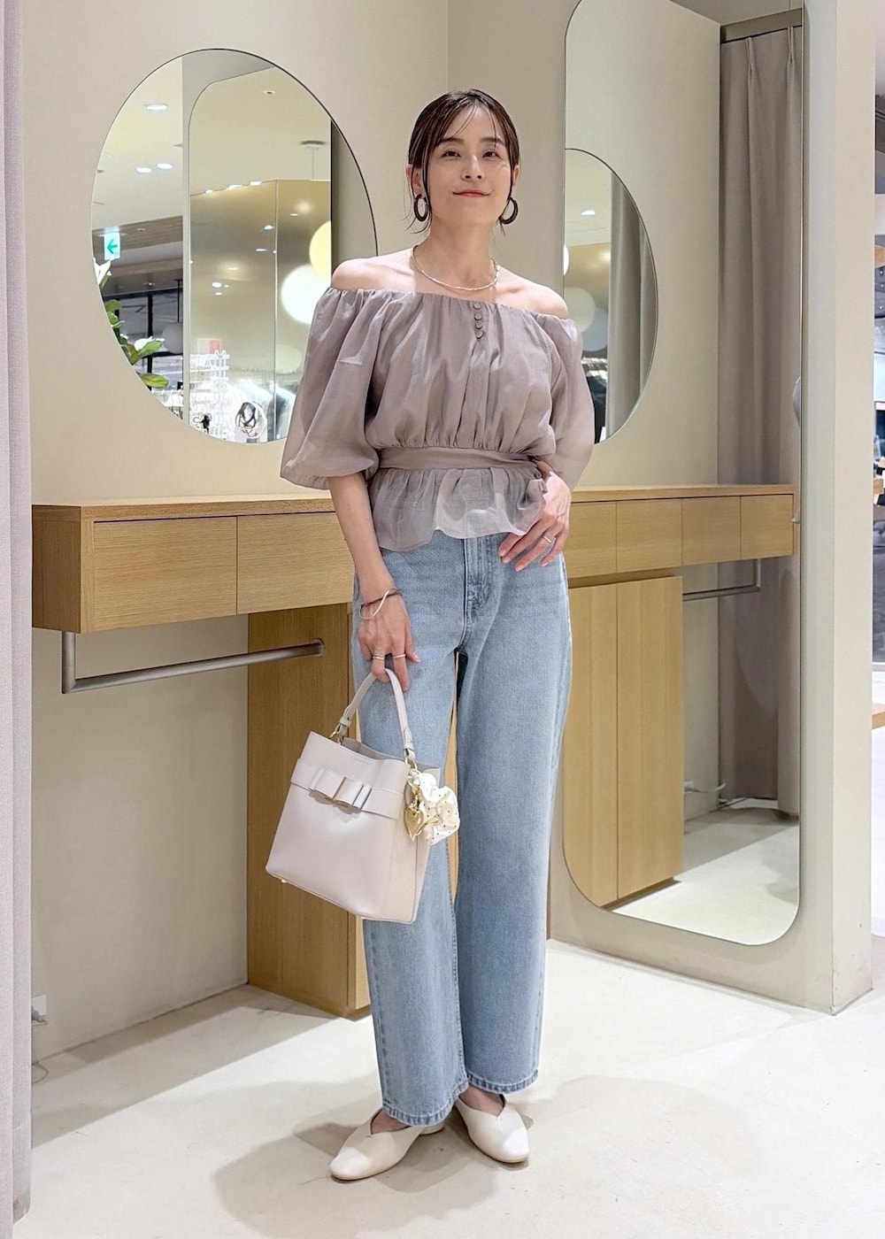 ホワイト系のパンプス、ベージュ系のシャツ/ブラウス、ブルー系のデニムパンツを着用したレディースの夏コーディネートの5枚目の写真