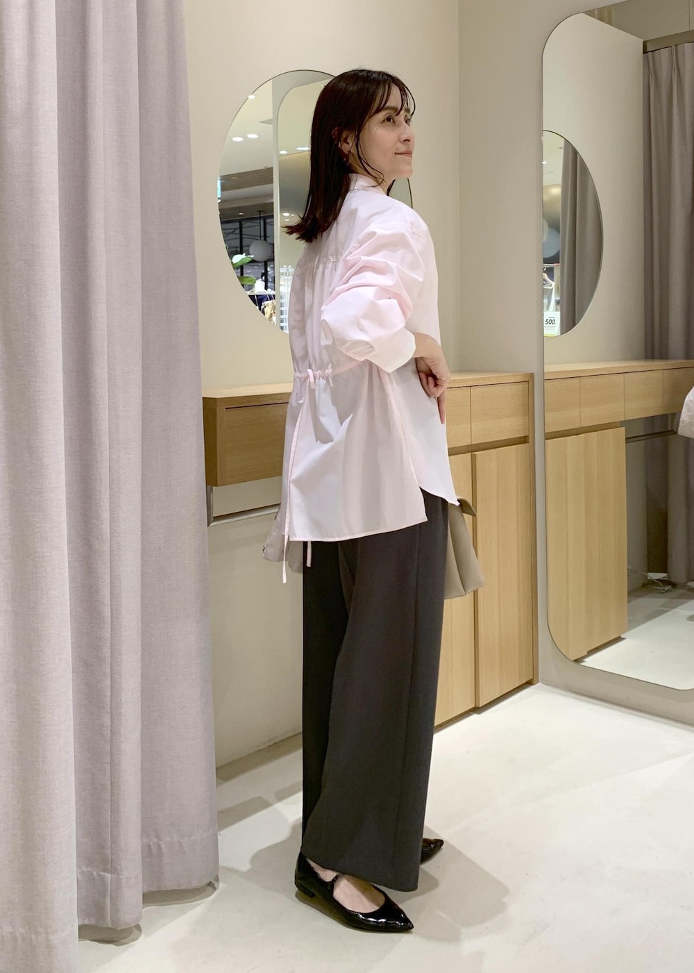 ベージュ系のハンドバッグ、ピンク系のナイロンジャケット、グレー系のスラックスを着用したレディースの春コーディネートの8枚目の写真