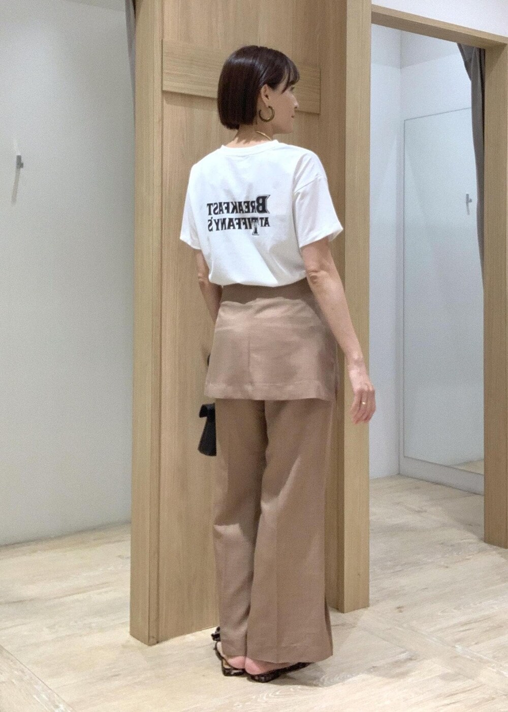 ホワイト系のTシャツ/カットソー、その他のサンダル、ブラウン系のスラックスを着用したレディースの夏コーディネートの5枚目の写真
