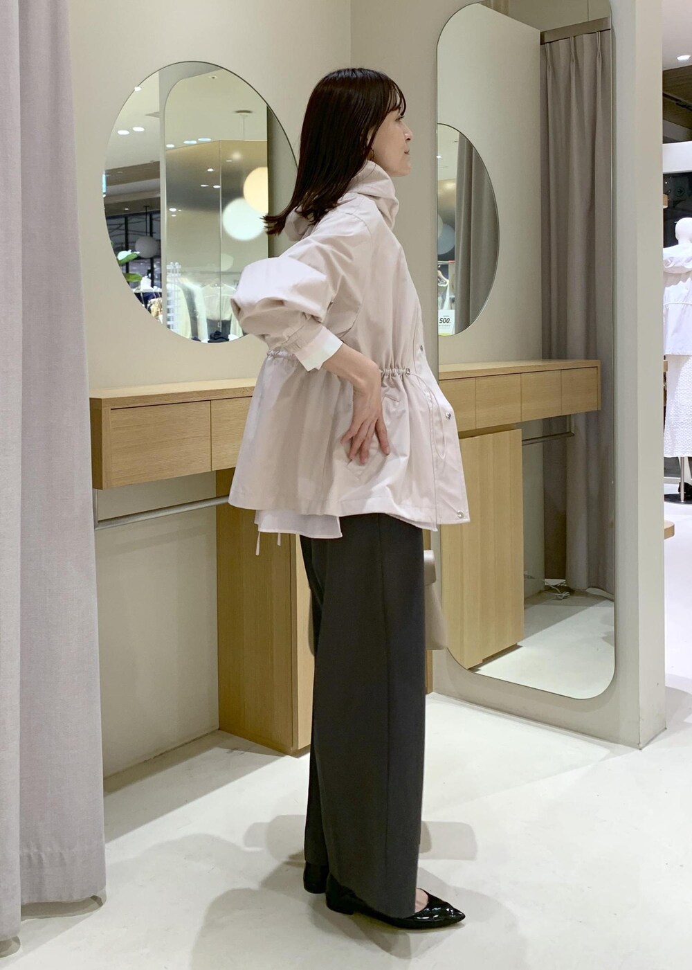 ベージュ系のハンドバッグ、ピンク系のナイロンジャケット、グレー系のスラックスを着用したレディースの春コーディネートの4枚目の写真