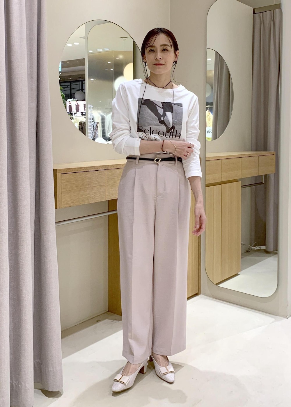 ホワイト系のショルダーバッグ、ベージュ系のパンプス、ホワイト系のナイロンジャケットを着用したレディースの春コーディネートの5枚目の写真