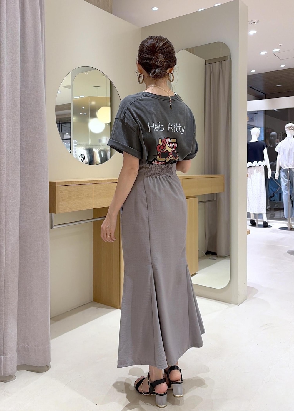 ブラック系のショルダーバッグ、グレー系のスカート、ブラック系のサンダルを着用したレディースの夏コーディネートの6枚目の写真
