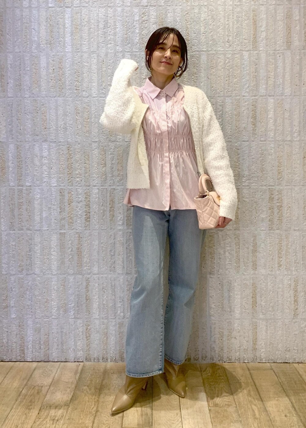 ベージュ系のブーツ、ブルー系のデニムパンツ、ピンク系のシャツ/ブラウスを着用したレディースの冬コーディネートの2枚目の写真