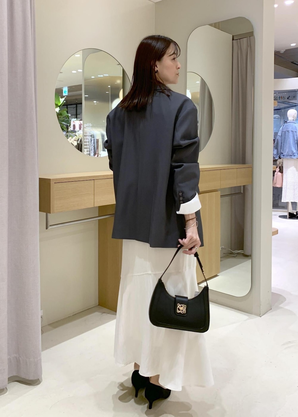 ブラック系のショルダーバッグ、ホワイト系のシャツ/ブラウス、ホワイト系のスカートを着用したレディースの春コーディネートの4枚目の写真