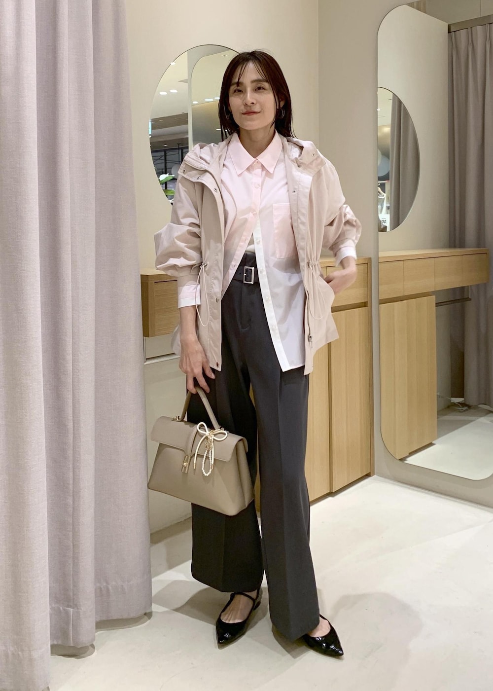 ベージュ系のハンドバッグ、ピンク系のナイロンジャケット、グレー系のスラックスを着用したレディースの春コーディネートの3枚目の写真