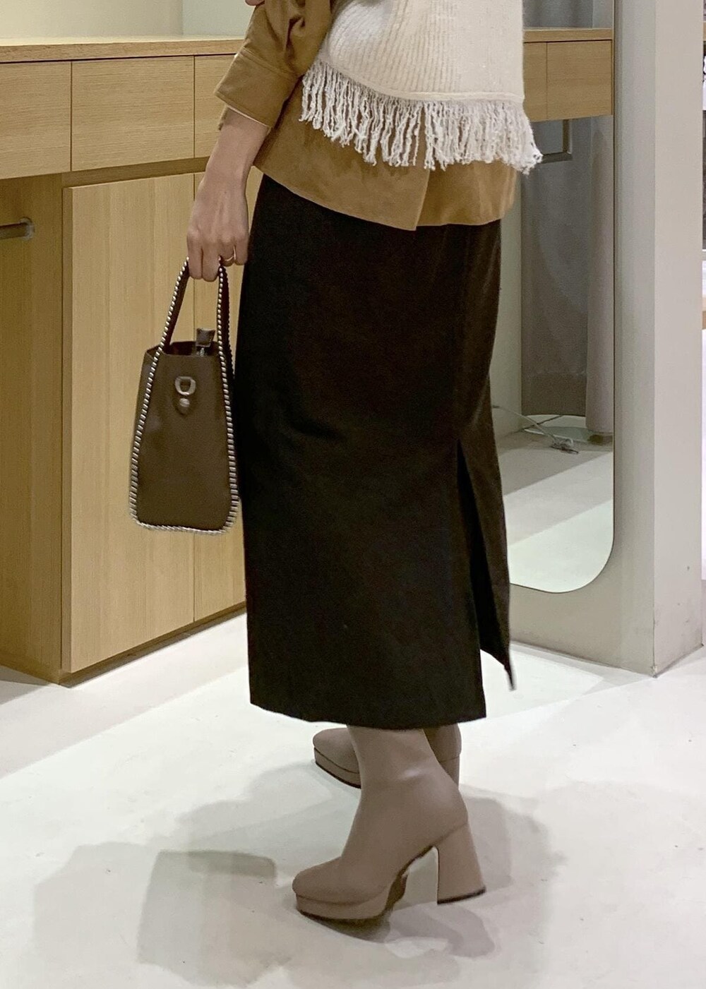 ベージュ系のブーツ、ブラウン系のスカート、イエロー系のシャツ/ブラウスを着用したレディースの秋コーディネートの9枚目の写真