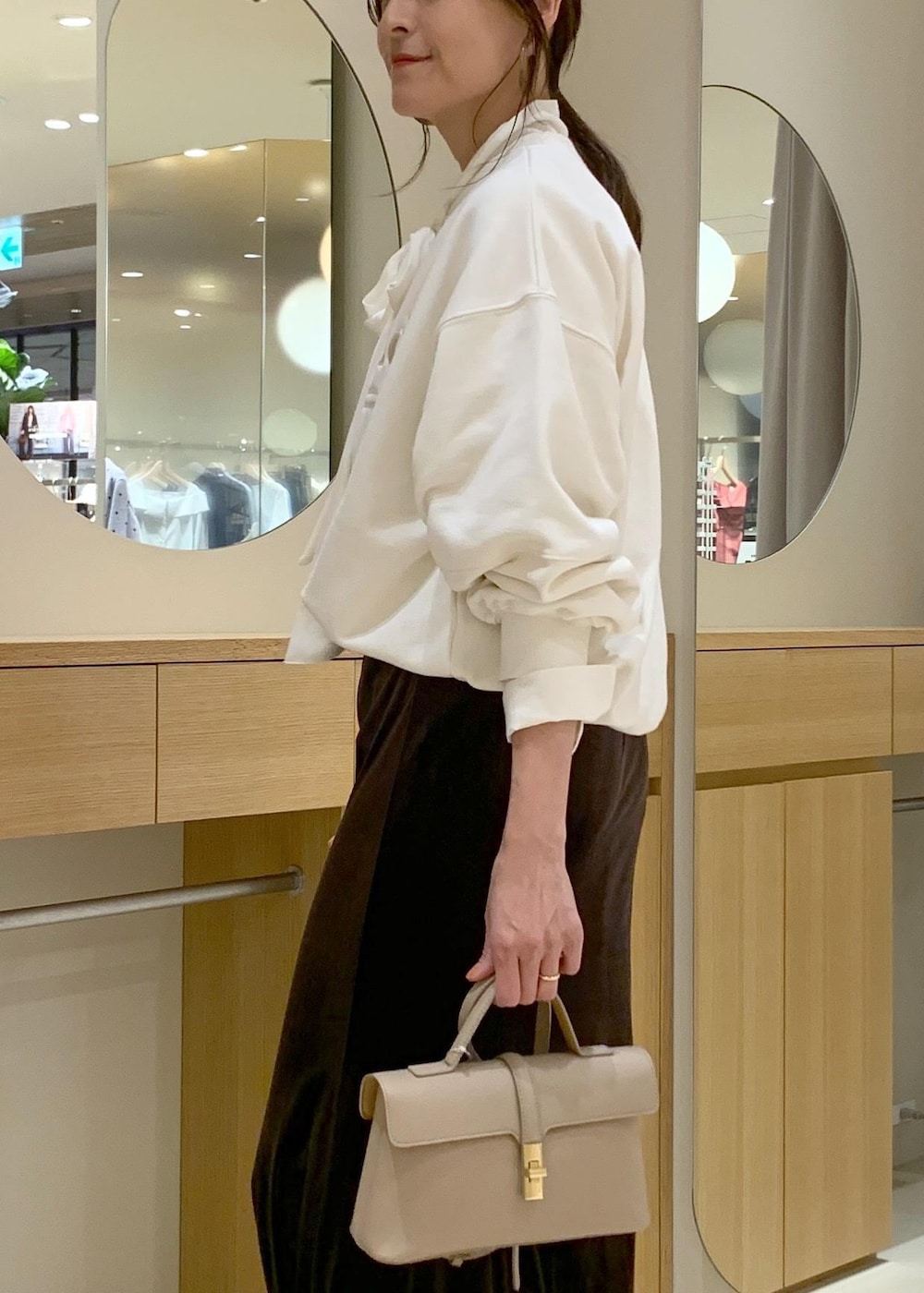 ベージュ系のショルダーバッグ、ブラウン系のスカート、ベージュ系のブーツを着用したレディースの秋コーディネートの6枚目の写真