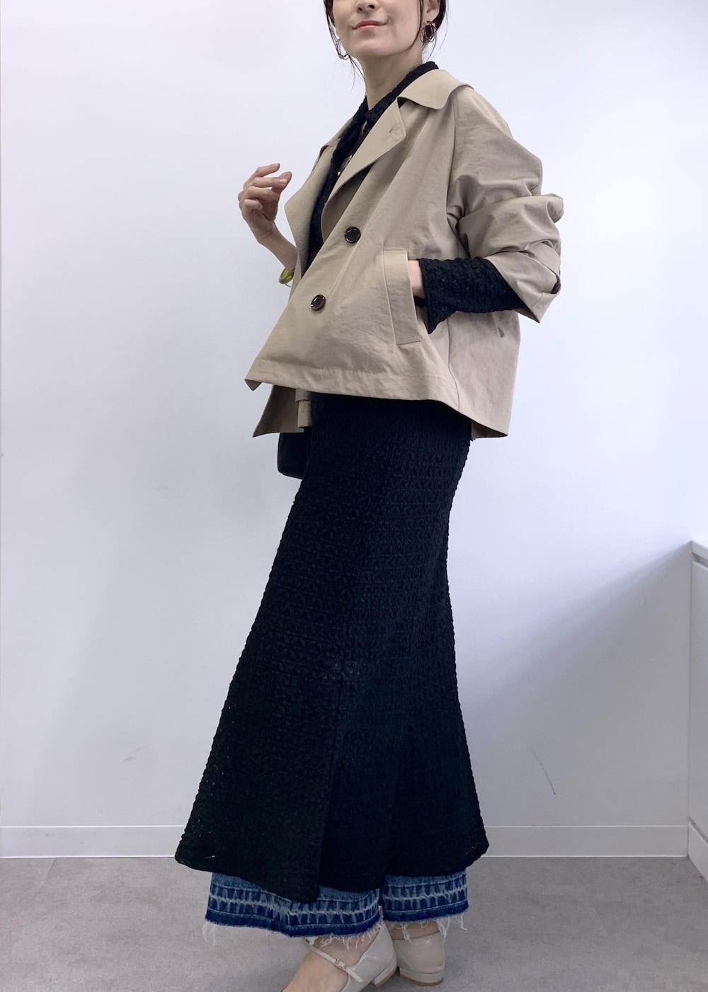 ブラック系のショルダーバッグ、ベージュ系のトレンチコート、ブルー系のデニムパンツを着用したレディースの冬コーディネートの5枚目の写真