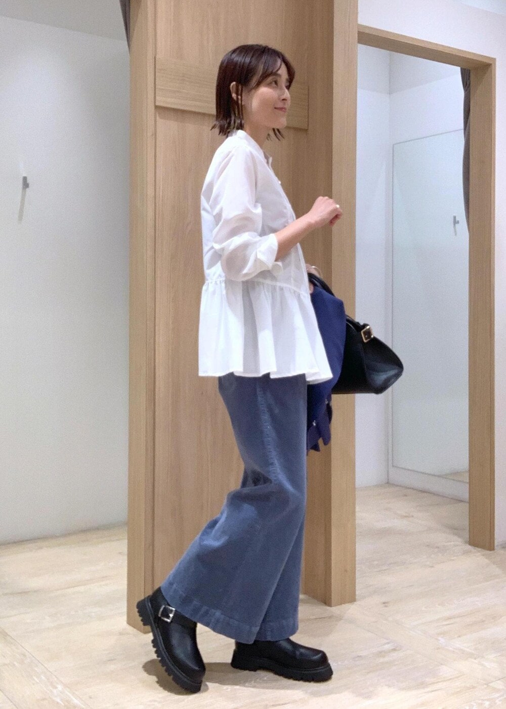 ブラック系のブーツ、ブラック系のトートバッグ、ブルー系のカーディガン/ボレロを着用したレディースの秋コーディネートの7枚目の写真