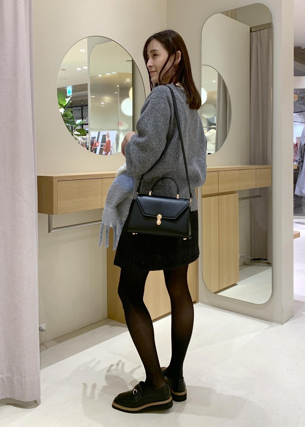 ブラック系のローファー、ブラック系のハンドバッグ、ブラック系のスカートを着用したレディースの冬コーディネートの2枚目の写真