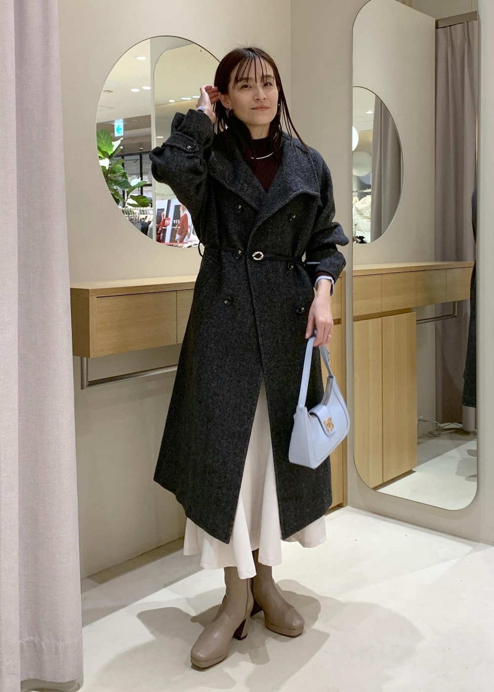 ブルー系のハンドバッグ、グレー系のその他アウター、ベージュ系のブーツを着用したレディースの冬コーディネートの2枚目の写真