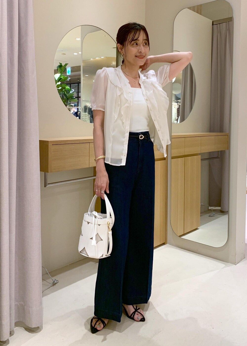 ホワイト系のキャミソール、ブラック系のサンダル、ブルー系のデニムパンツを着用したレディースの夏コーディネートの2枚目の写真