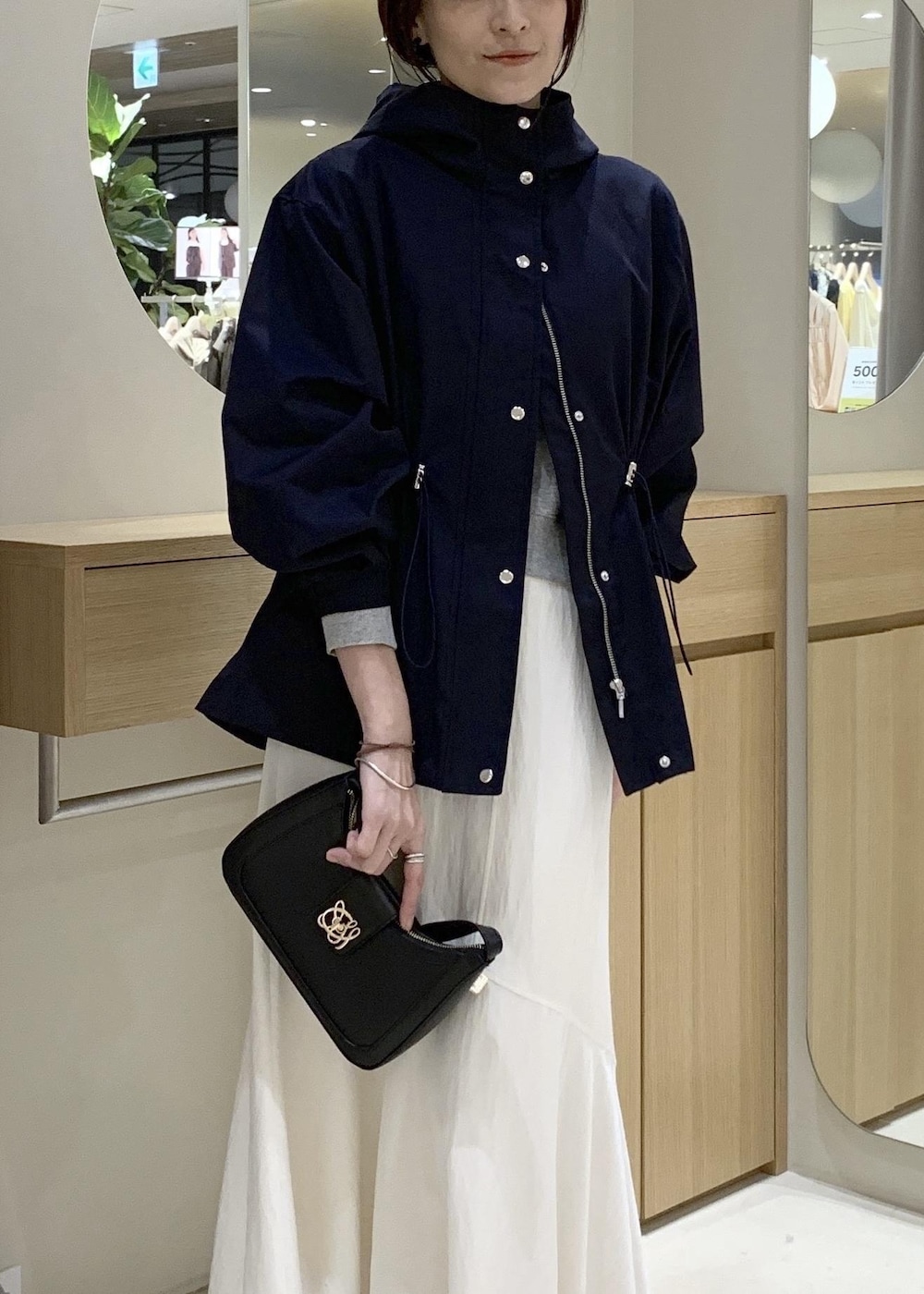 ブラック系のショルダーバッグ、ブルー系のナイロンジャケット、ホワイト系のキャミソールを着用したレディースの春コーディネートの5枚目の写真