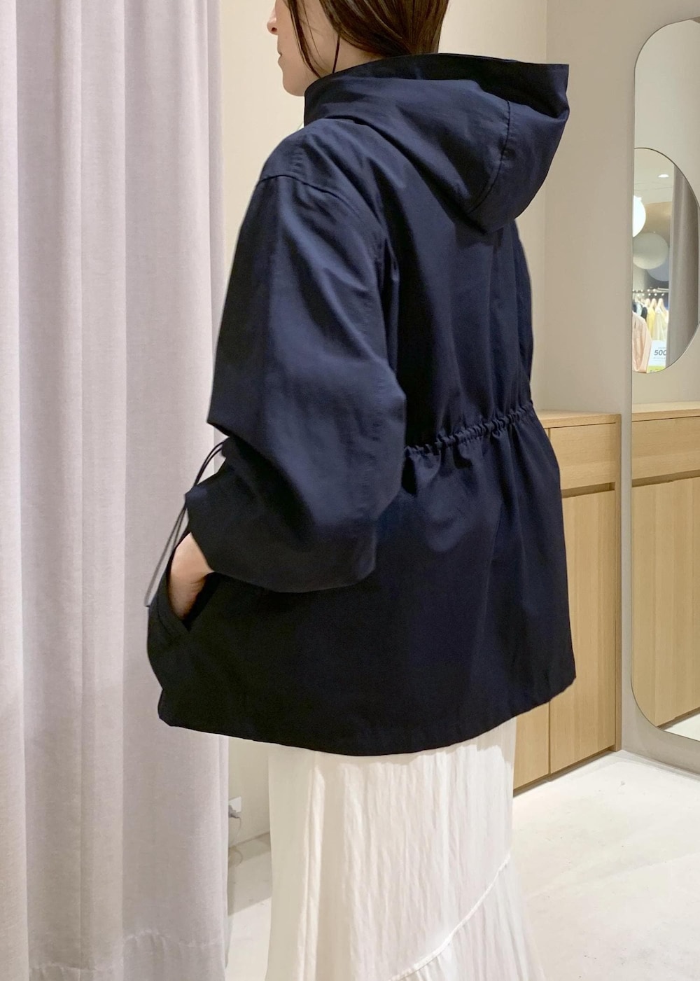 ブラック系のショルダーバッグ、ブルー系のナイロンジャケット、ホワイト系のキャミソールを着用したレディースの春コーディネートの6枚目の写真