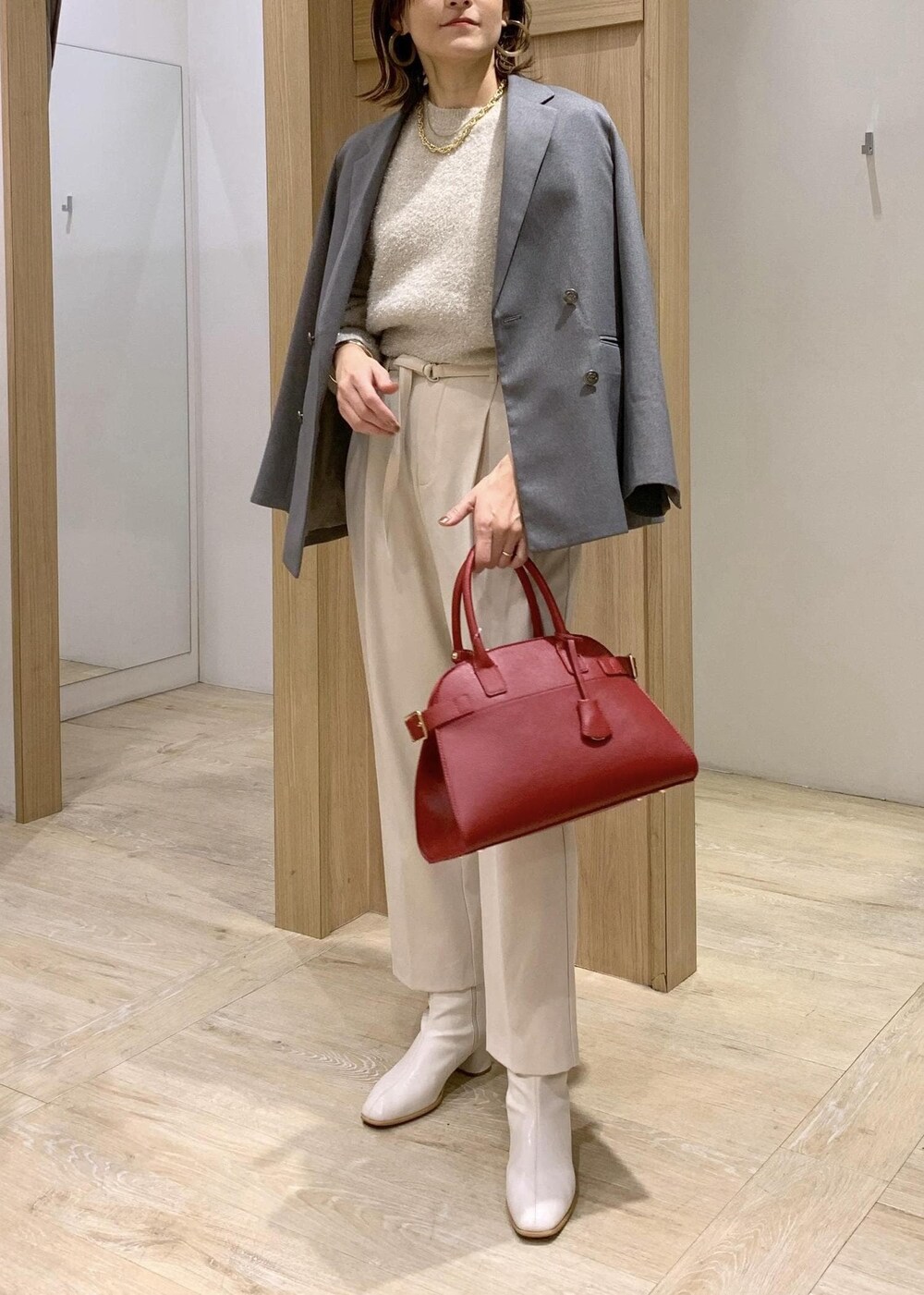 レッド系のトートバッグ、ホワイト系のブーツ、グレー系のテーラードジャケットを着用したレディースの冬コーディネートの3枚目の写真