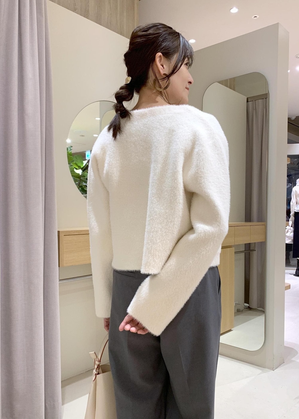 ベージュ系のショルダーバッグ、グレー系のスラックス、ホワイト系のカーディガン/ボレロを着用したレディースの冬コーディネートの6枚目の写真