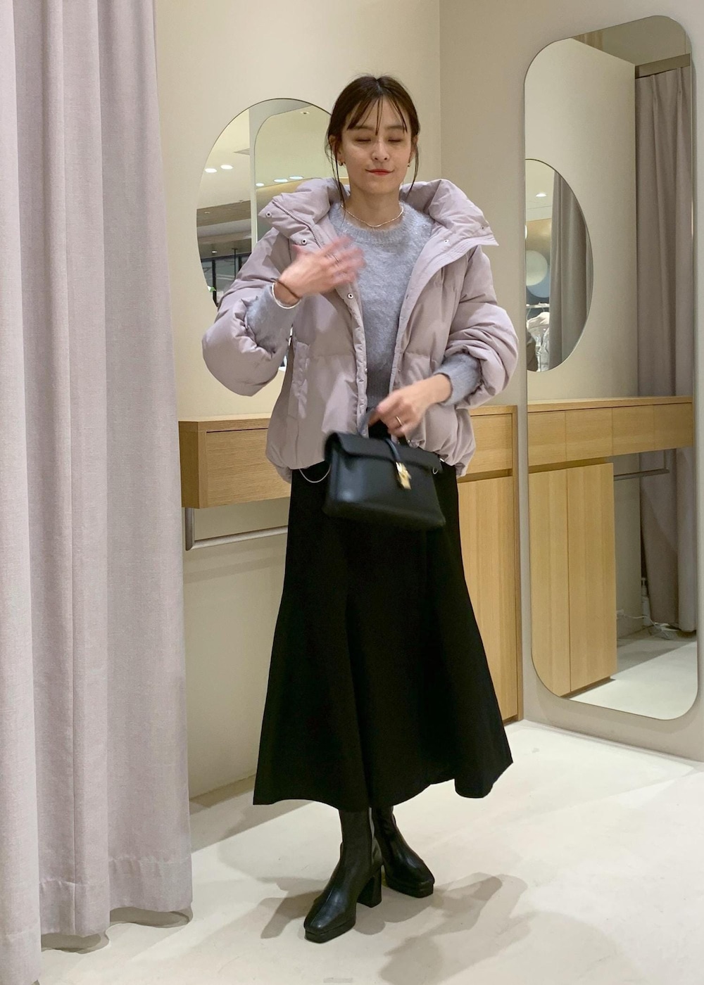 ブラック系のショルダーバッグ、ブラック系のブーツ、ブラック系のスカートを着用したレディースの秋コーディネートの2枚目の写真