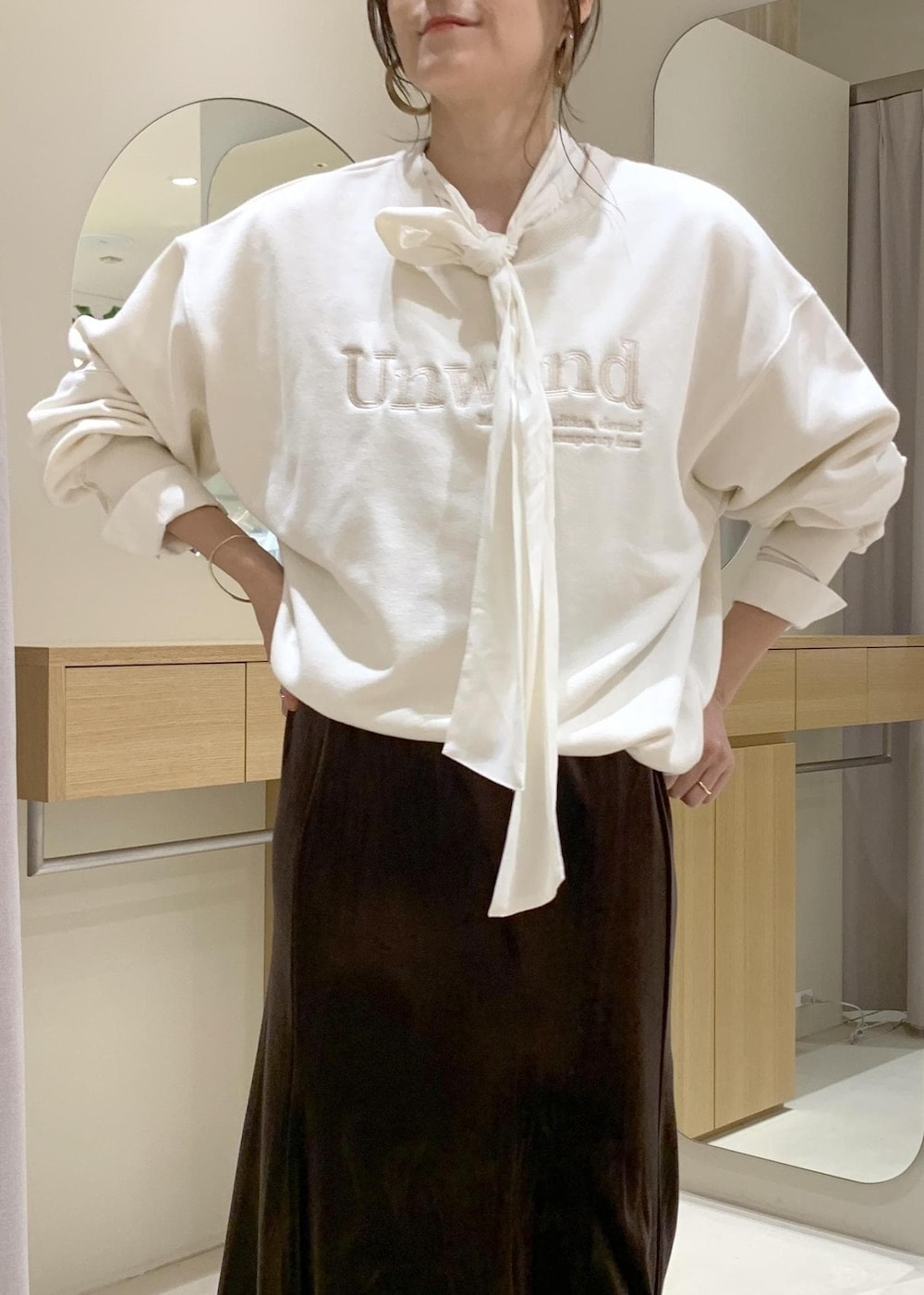 ベージュ系のショルダーバッグ、ブラウン系のスカート、ベージュ系のブーツを着用したレディースの秋コーディネートの5枚目の写真