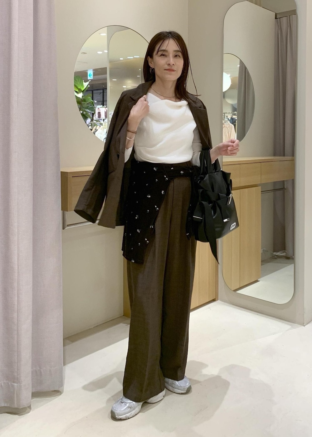 ブラック系のトートバッグ、ブラウン系のカーディガン/ボレロ、ホワイト系のニット/セーターを着用したレディースの春コーディネートの2枚目の写真
