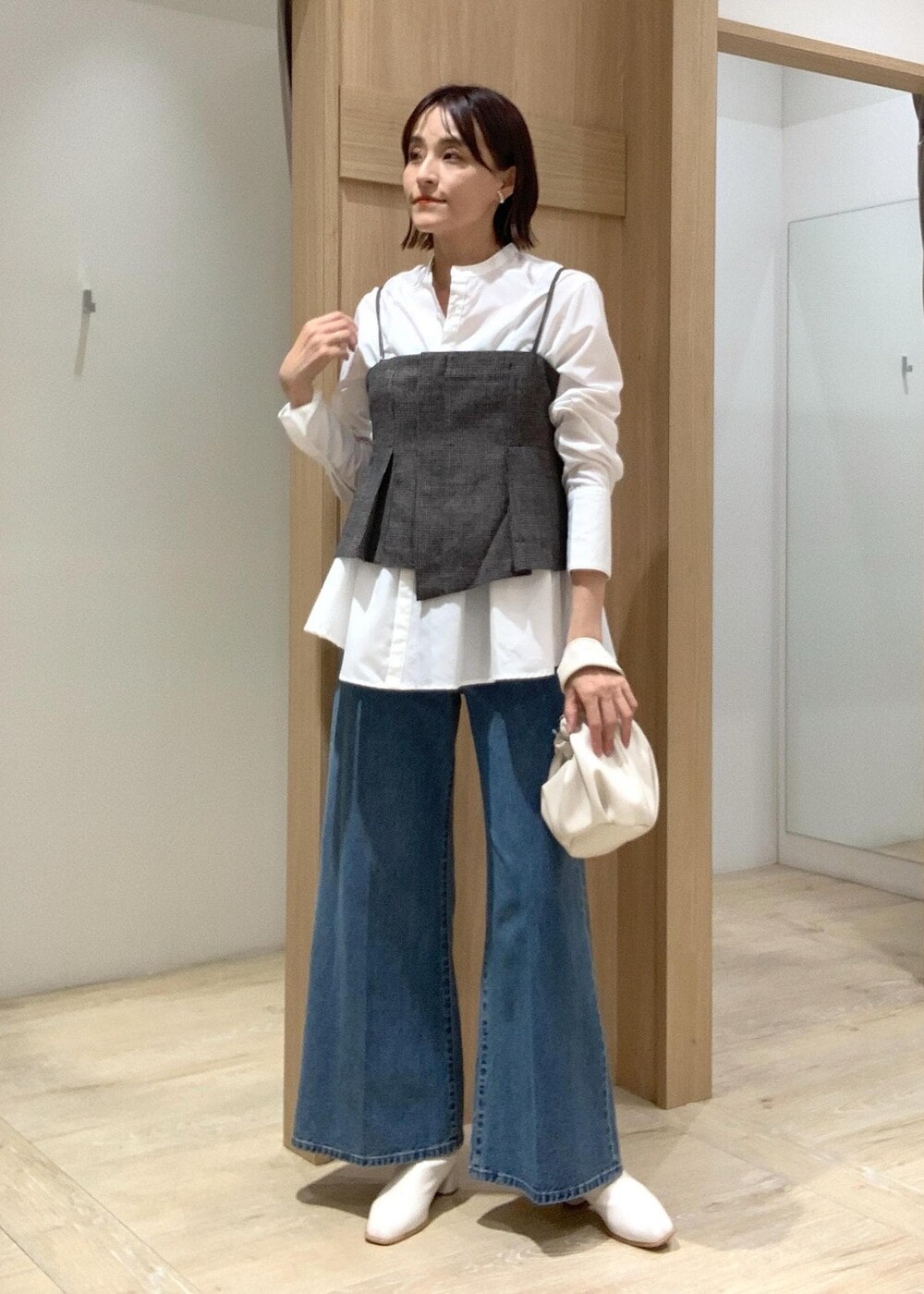 ホワイト系のハンドバッグ、ブルー系のデニムパンツ、ホワイト系のブーツを着用したレディースの秋コーディネートの3枚目の写真