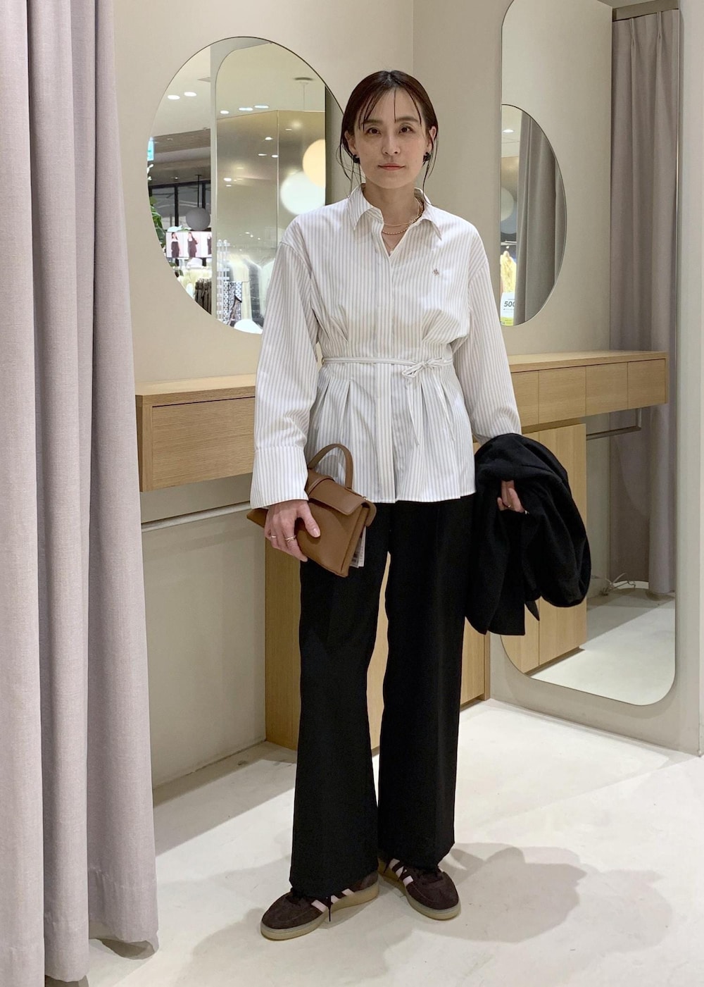 イエロー系のショルダーバッグ、ブラック系のテーラードジャケット、ブラック系のその他パンツを着用したレディースの春コーディネートの6枚目の写真