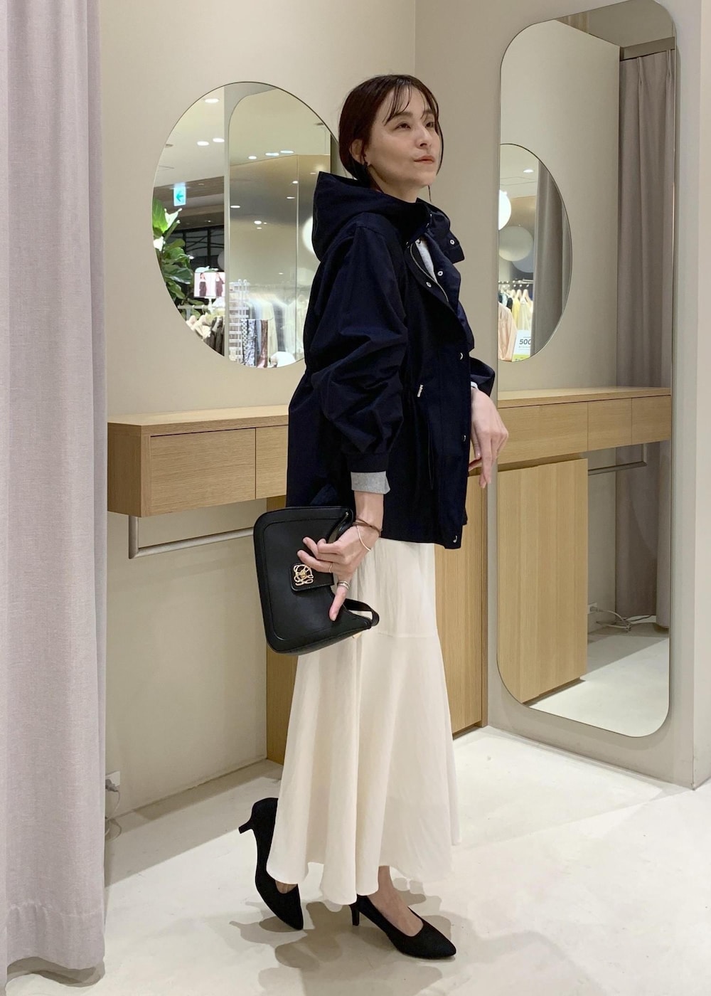 ブラック系のショルダーバッグ、ブルー系のナイロンジャケット、ホワイト系のキャミソールを着用したレディースの春コーディネートの3枚目の写真