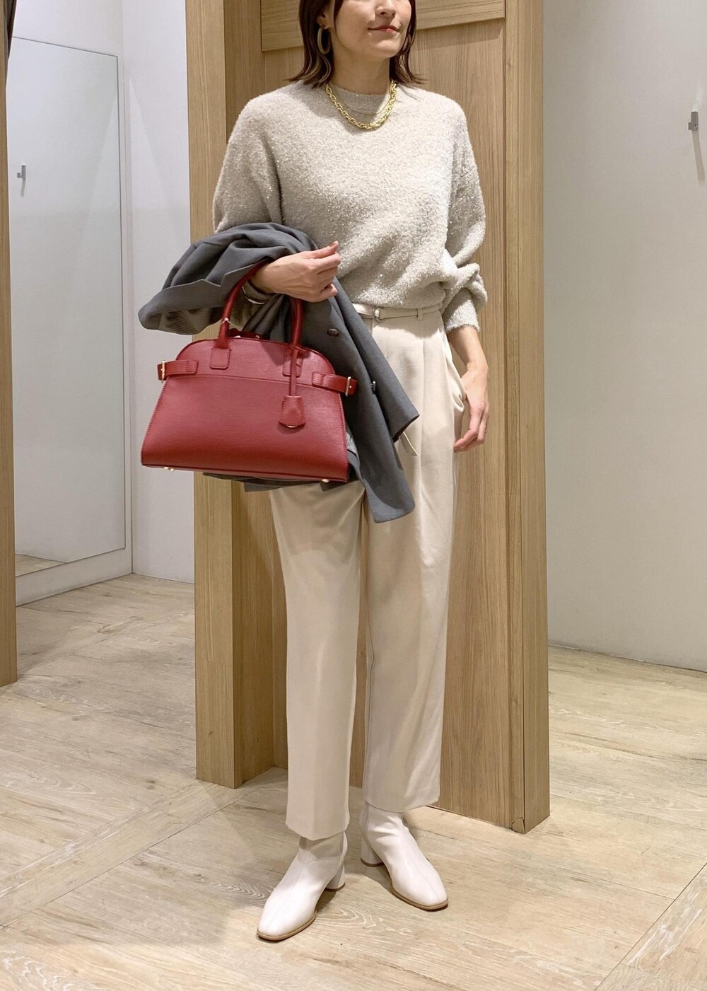 レッド系のトートバッグ、ホワイト系のブーツ、グレー系のテーラードジャケットを着用したレディースの冬コーディネートの8枚目の写真