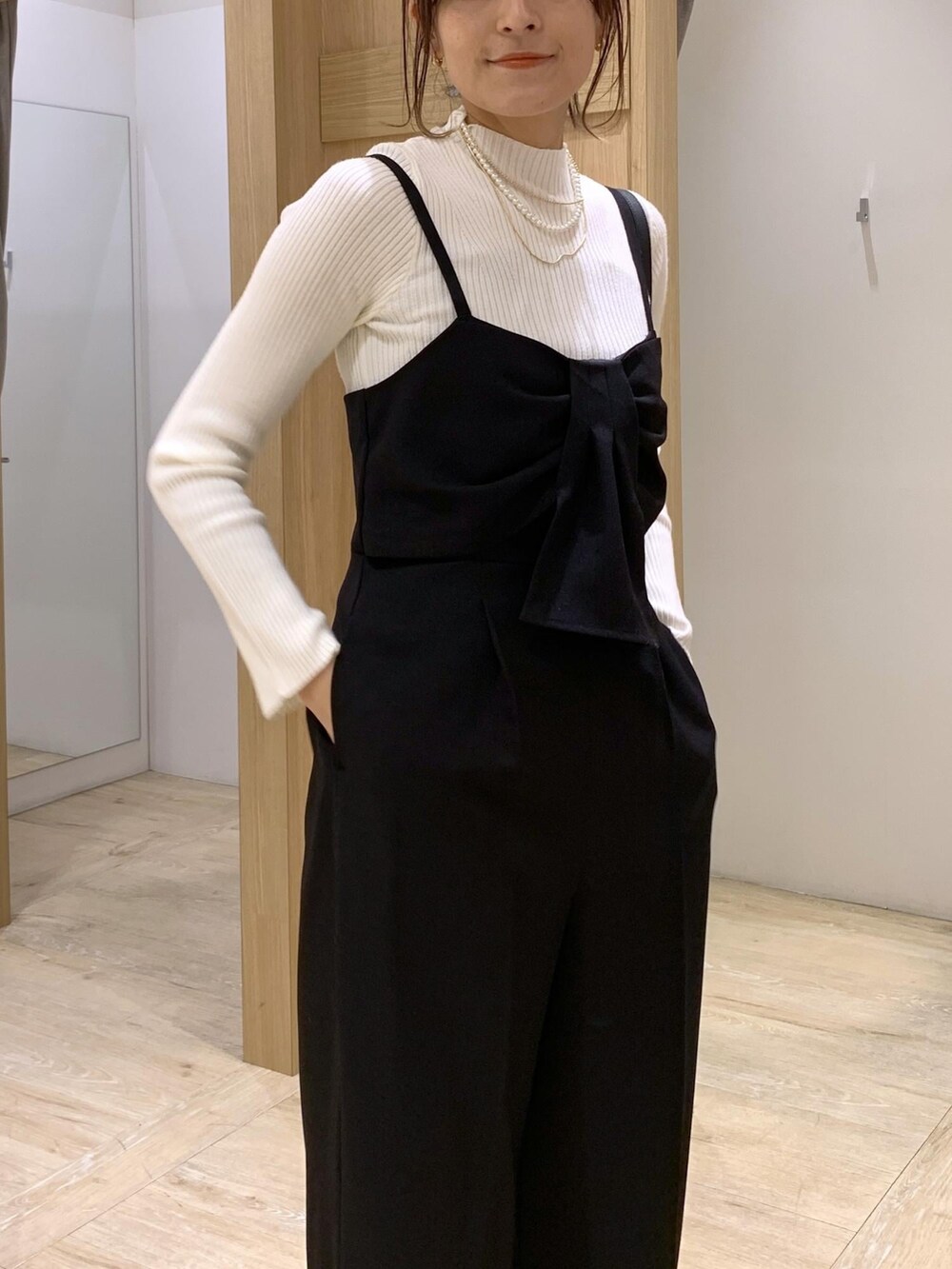 イエロー系のカーディガン/ボレロ、ホワイト系のニット/セーター、ブラック系のサロペット/オーバーオールを着用したレディースの冬コーディネートの7枚目の写真