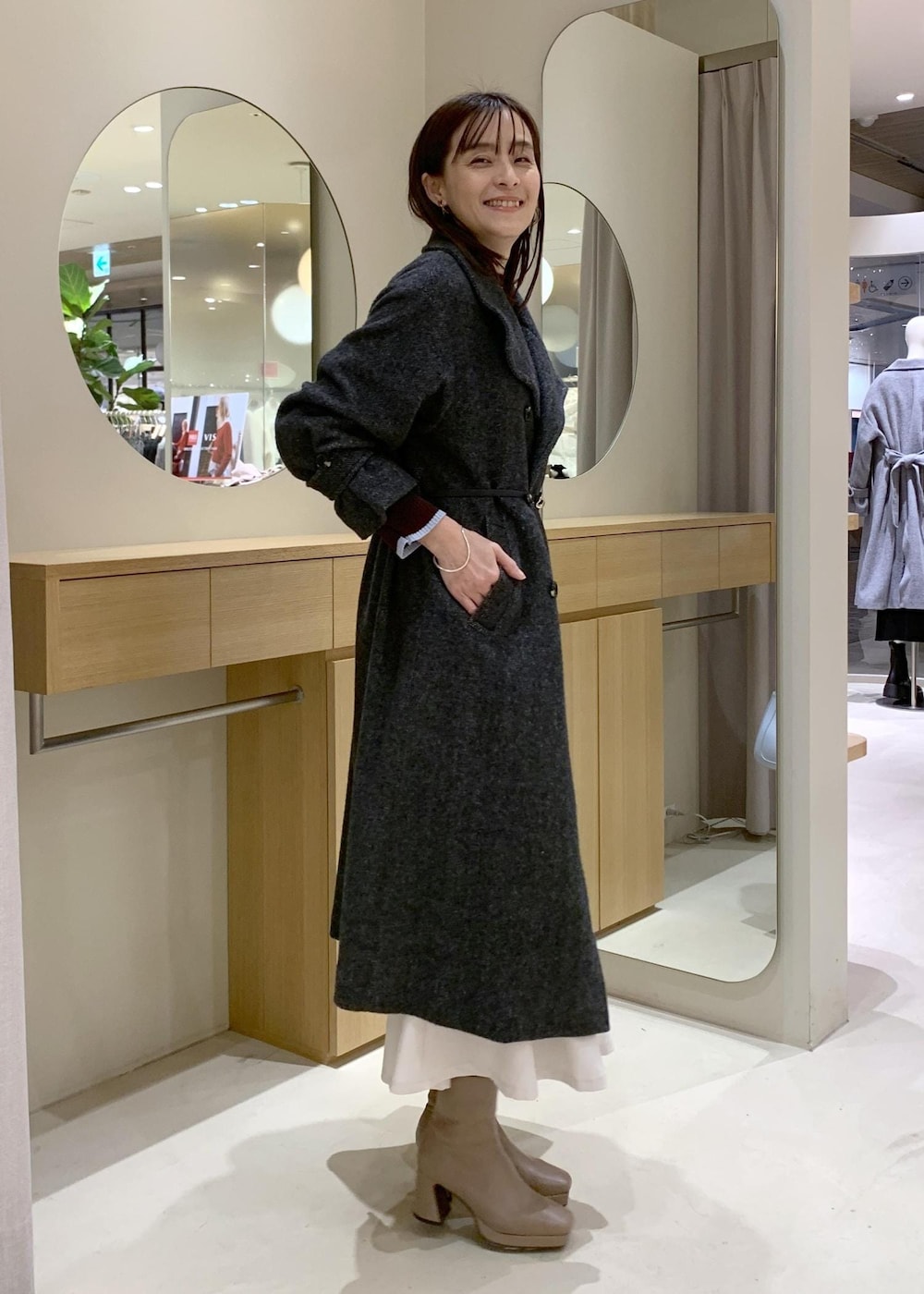 ブルー系のハンドバッグ、グレー系のその他アウター、ベージュ系のブーツを着用したレディースの冬コーディネートの3枚目の写真