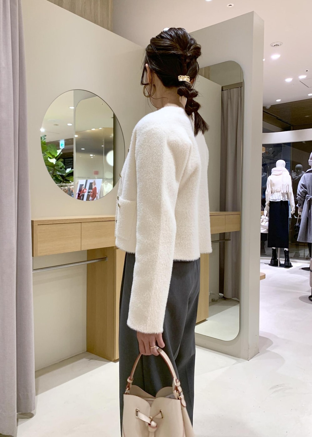 ベージュ系のショルダーバッグ、グレー系のスラックス、ホワイト系のカーディガン/ボレロを着用したレディースの冬コーディネートの5枚目の写真