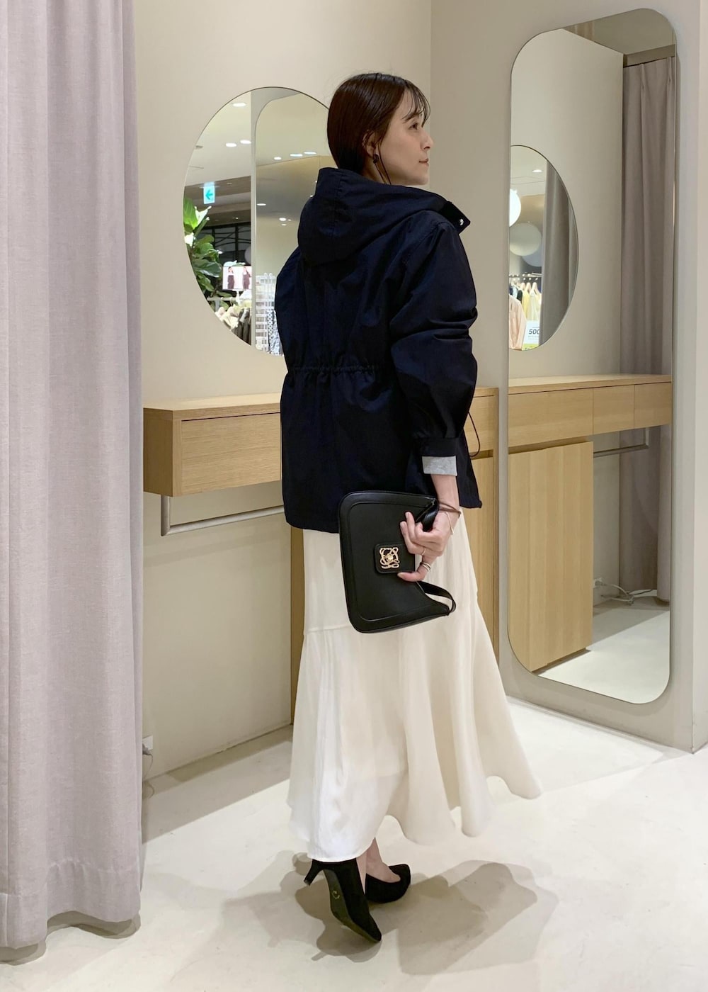 ブラック系のショルダーバッグ、ブルー系のナイロンジャケット、ホワイト系のキャミソールを着用したレディースの春コーディネートの4枚目の写真