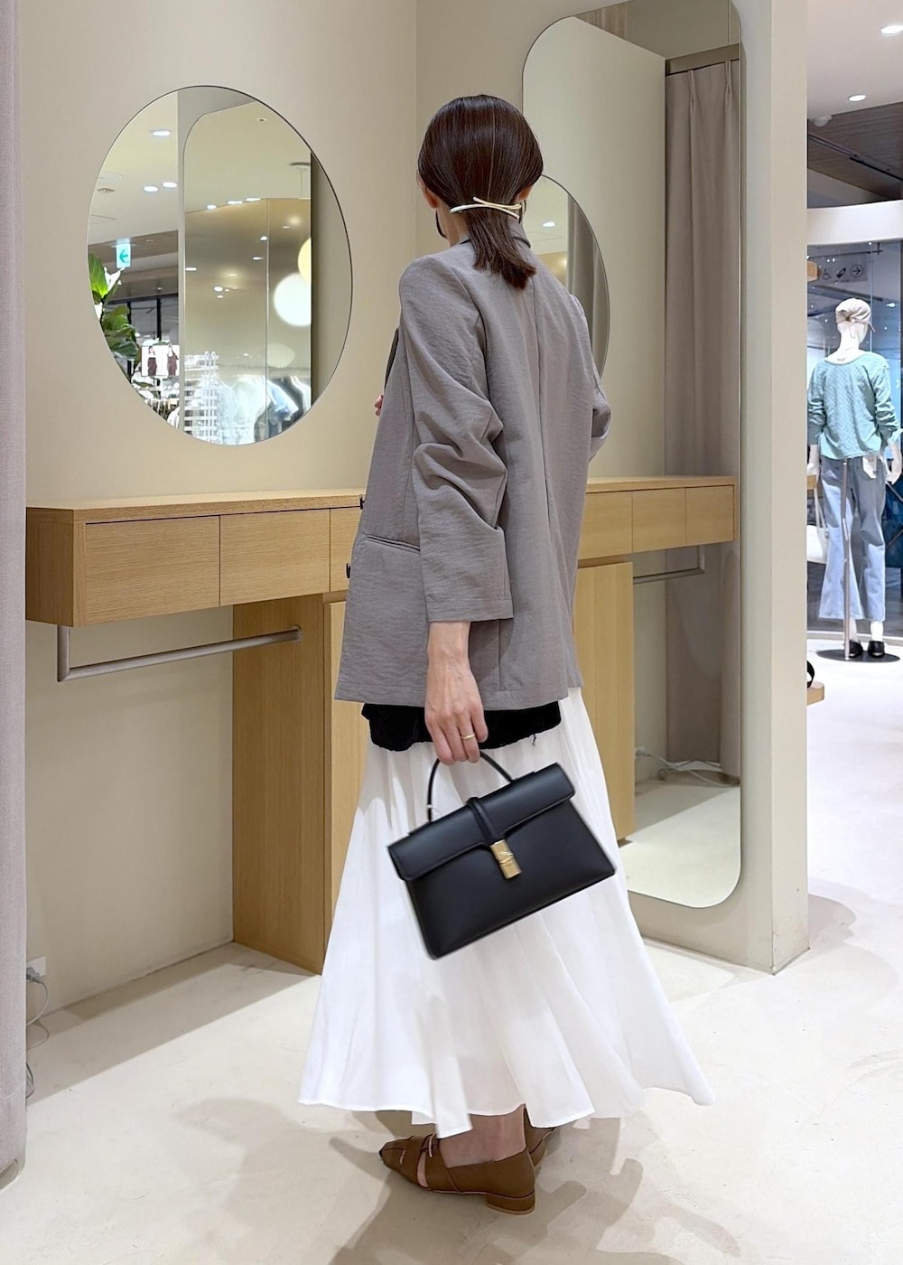 ブラウン系のパンプス、ホワイト系のスカート、ブラック系のカーディガン/ボレロを着用したレディースの春コーディネートの4枚目の写真