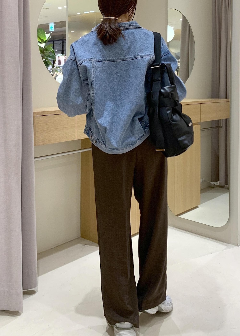 ブルー系のデニムジャケット、ブラック系のトートバッグ、ブラウン系のカーディガン/ボレロを着用したレディースの春コーディネートの4枚目の写真