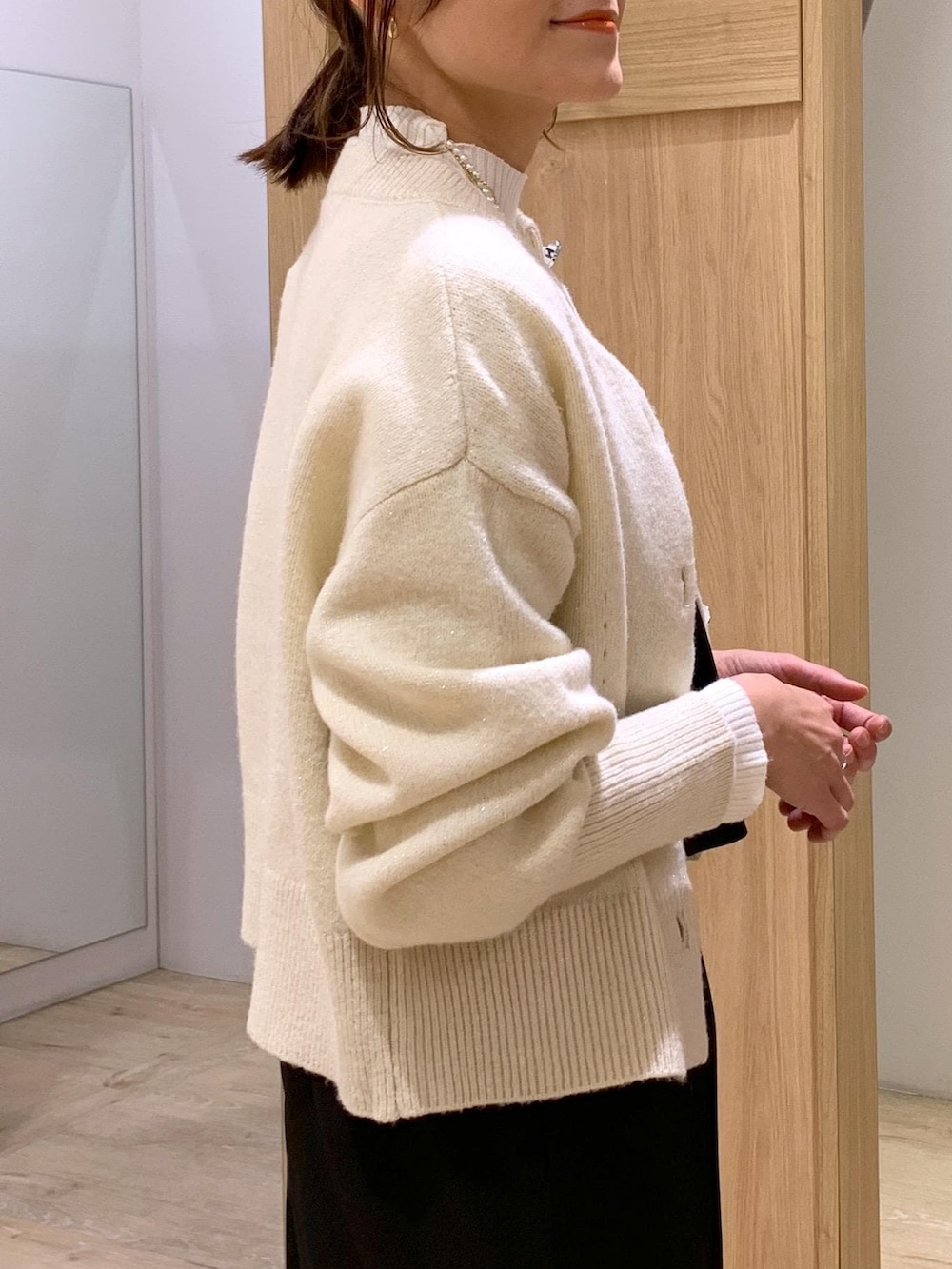 イエロー系のカーディガン/ボレロ、ホワイト系のニット/セーター、ブラック系のサロペット/オーバーオールを着用したレディースの冬コーディネートの5枚目の写真