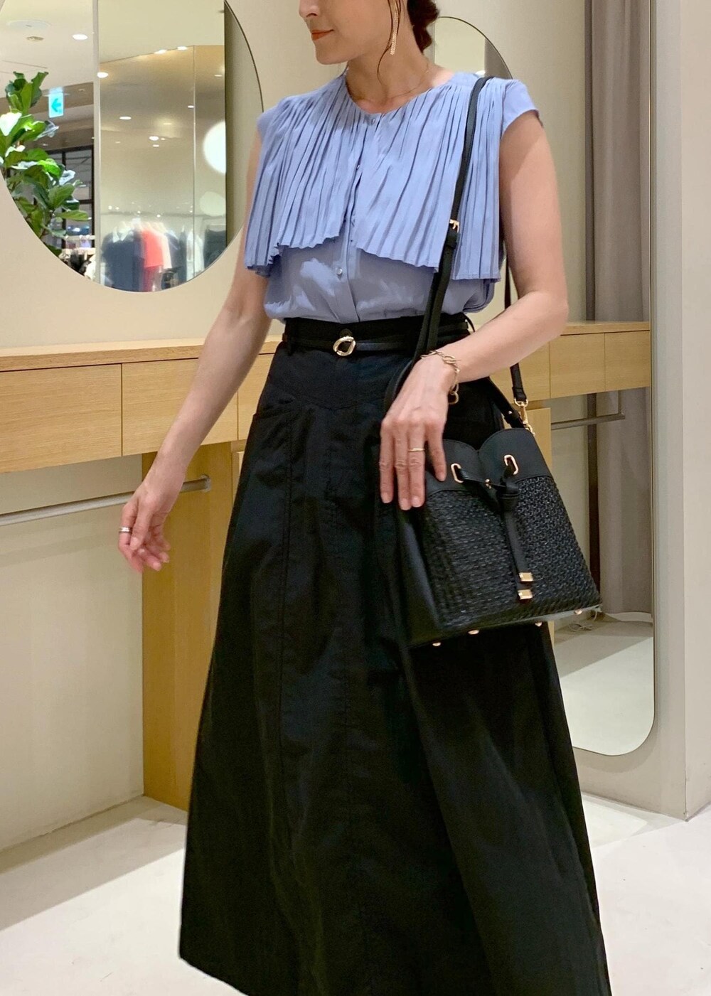 ブラック系のショルダーバッグ、ブルー系のシャツ/ブラウス、ブラック系のスカートを着用したレディースの夏コーディネートの3枚目の写真