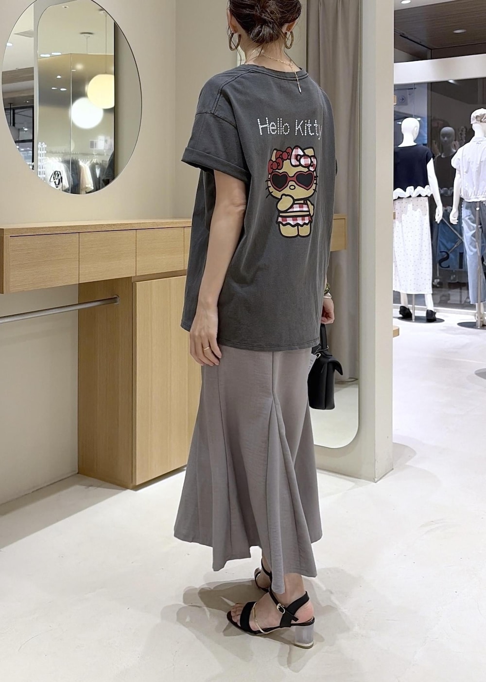 ブラック系のショルダーバッグ、グレー系のスカート、ブラック系のサンダルを着用したレディースの夏コーディネートの8枚目の写真