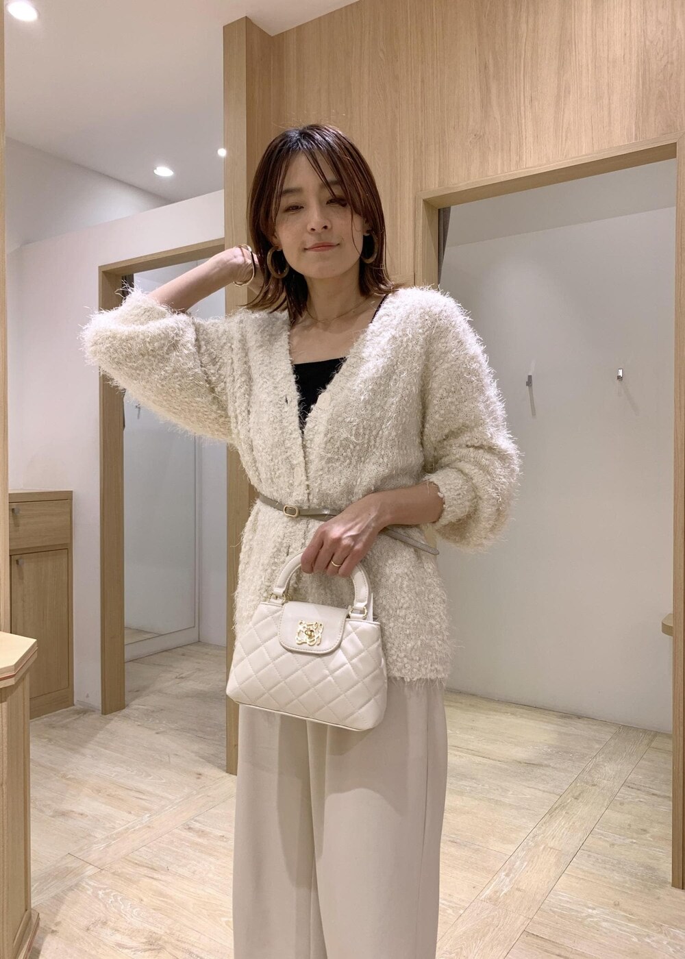 ブラック系のキャミソール、ホワイト系のカーディガン/ボレロ、ベージュ系のその他パンツを着用したレディースの冬コーディネートの4枚目の写真