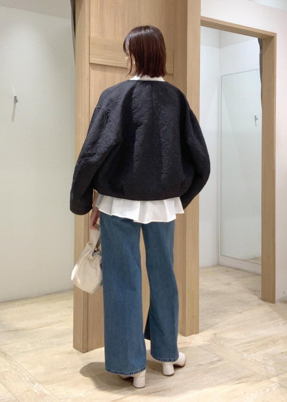 ホワイト系のハンドバッグ、ブルー系のデニムパンツ、ホワイト系のブーツを着用したレディースの秋コーディネートの9枚目の写真