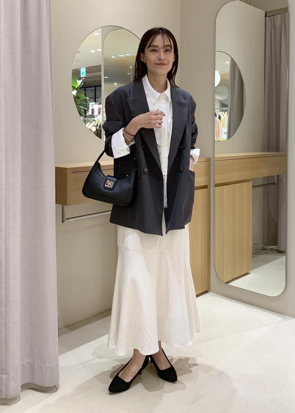 ブラック系のショルダーバッグ、ホワイト系のシャツ/ブラウス、ホワイト系のスカートを着用したレディースの春コーディネートの2枚目の写真