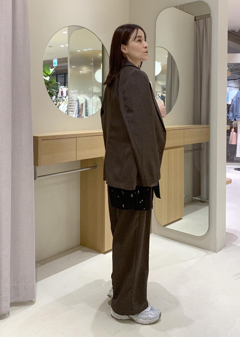 ブラック系のトートバッグ、ブラウン系のカーディガン/ボレロ、ホワイト系のニット/セーターを着用したレディースの春コーディネートの4枚目の写真