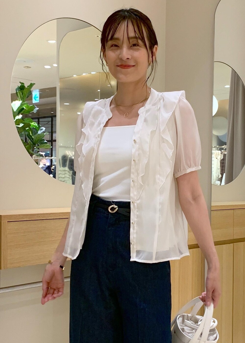 ホワイト系のキャミソール、ブラック系のサンダル、ブルー系のデニムパンツを着用したレディースの夏コーディネートの3枚目の写真