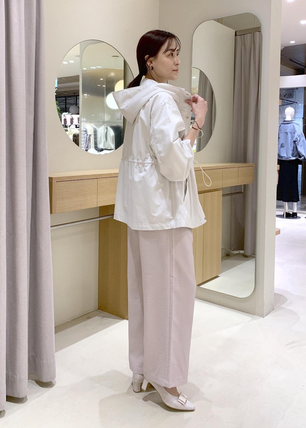 ホワイト系のショルダーバッグ、ベージュ系のパンプス、ホワイト系のナイロンジャケットを着用したレディースの春コーディネートの3枚目の写真