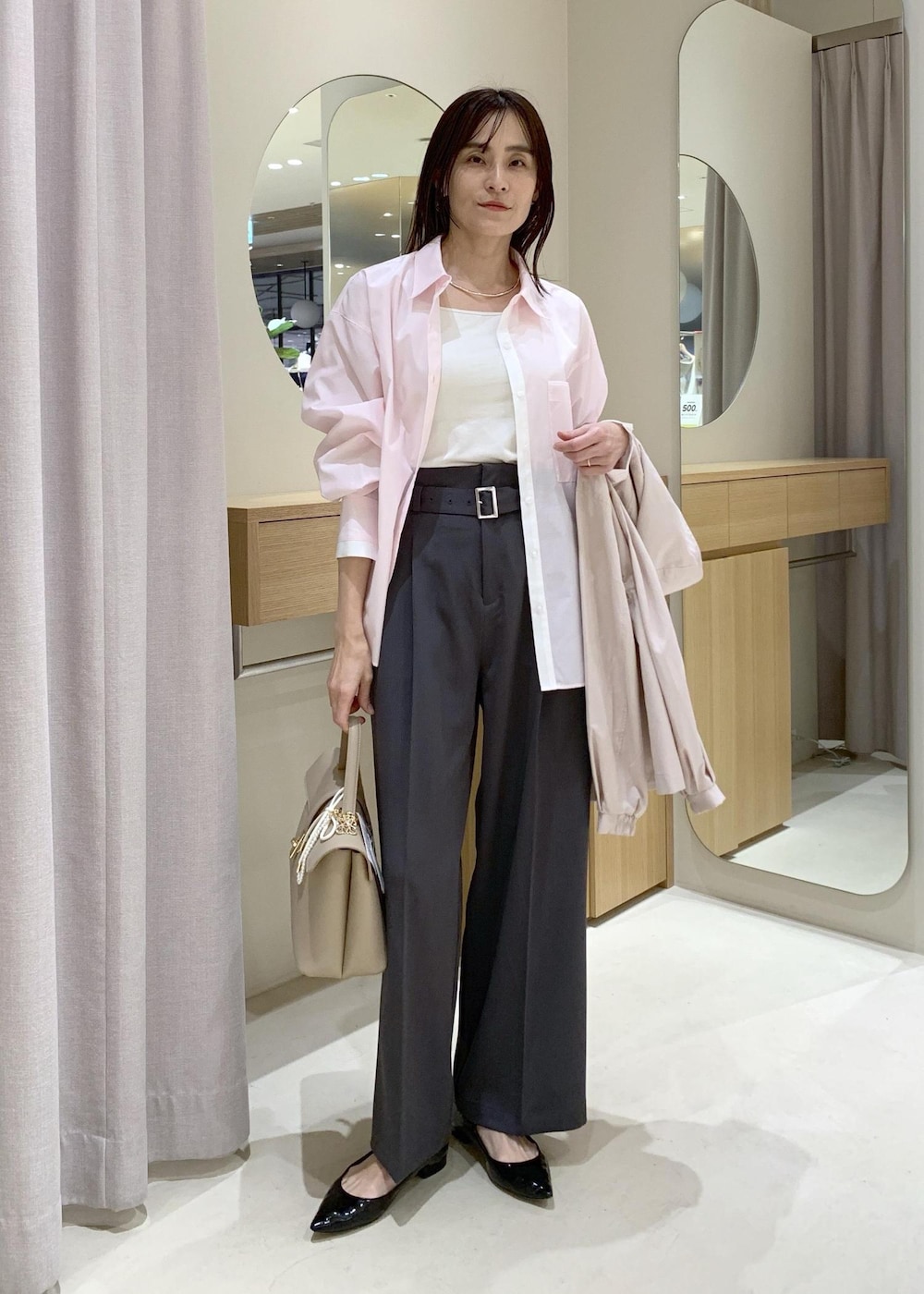 ベージュ系のハンドバッグ、ピンク系のナイロンジャケット、グレー系のスラックスを着用したレディースの春コーディネートの6枚目の写真