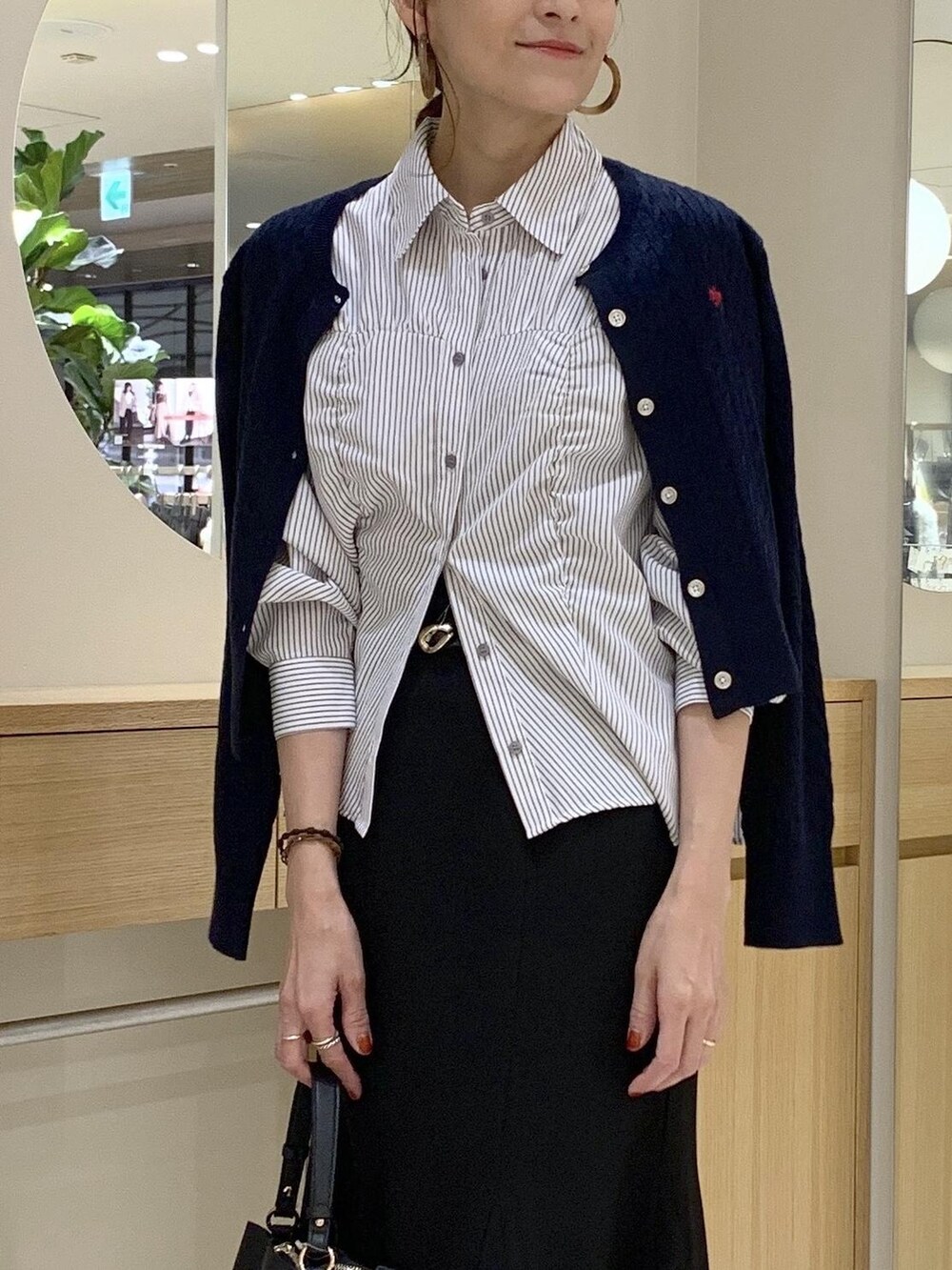 ブラック系のショルダーバッグ、ブラック系のスカート、ブルー系のカーディガン/ボレロを着用したレディースの秋コーディネートの7枚目の写真