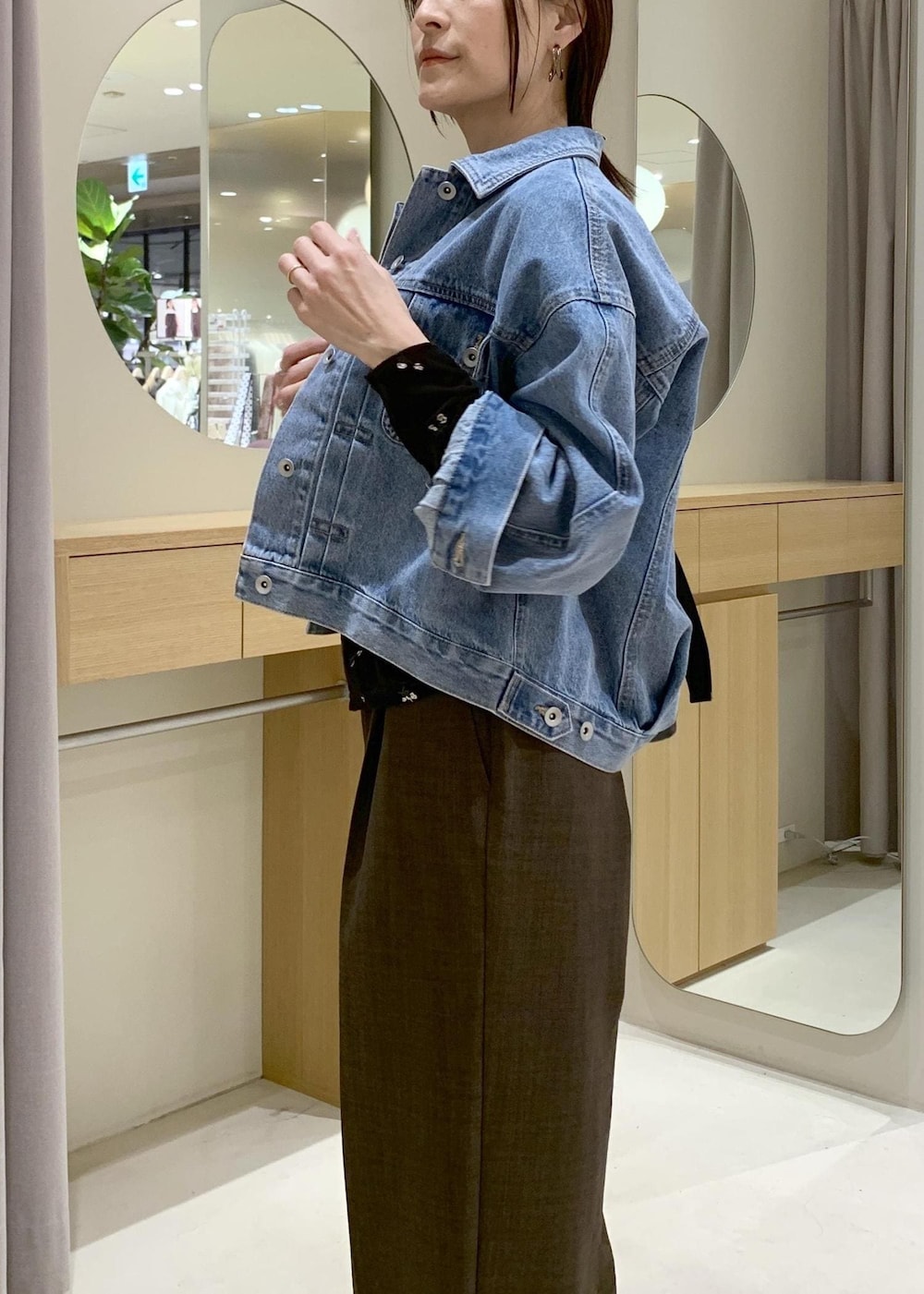 ブルー系のデニムジャケット、ブラック系のトートバッグ、ブラウン系のカーディガン/ボレロを着用したレディースの春コーディネートの6枚目の写真