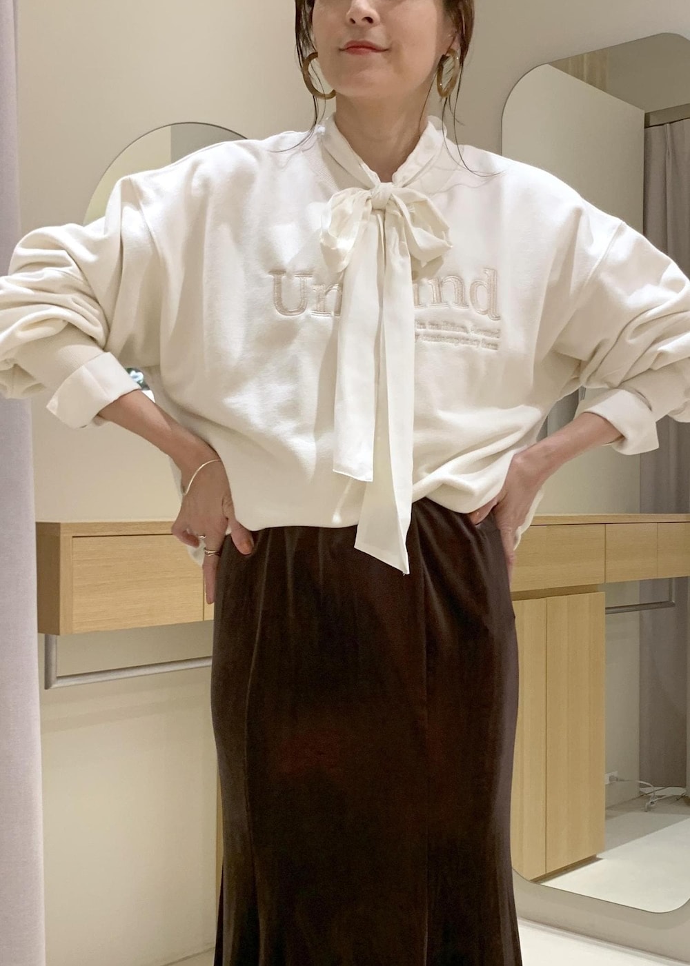 ベージュ系のショルダーバッグ、ブラウン系のスカート、ベージュ系のブーツを着用したレディースの秋コーディネートの4枚目の写真