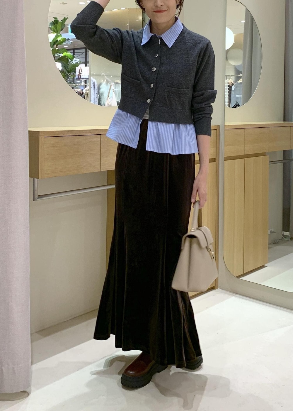 ベージュ系のハンドバッグ、ブラウン系のブーツ、ブラウン系のスカートを着用したレディースの秋コーディネートの2枚目の写真