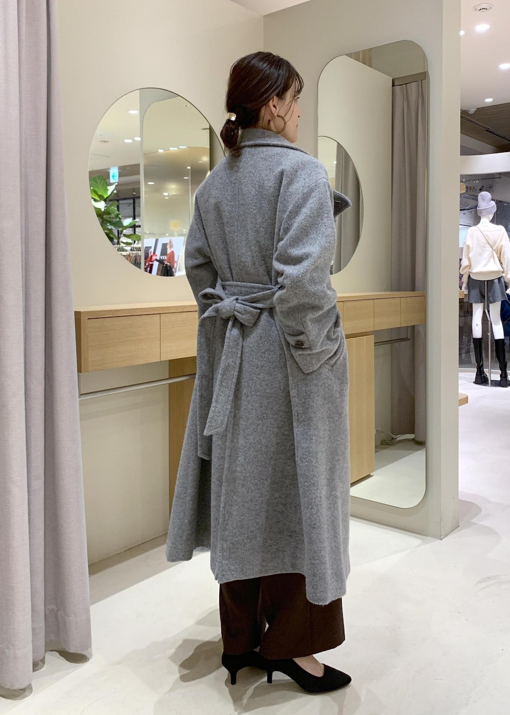 ブルー系のハンドバッグ、ブラウン系のスラックス、グレー系のその他アウターを着用したレディースの冬コーディネートの3枚目の写真